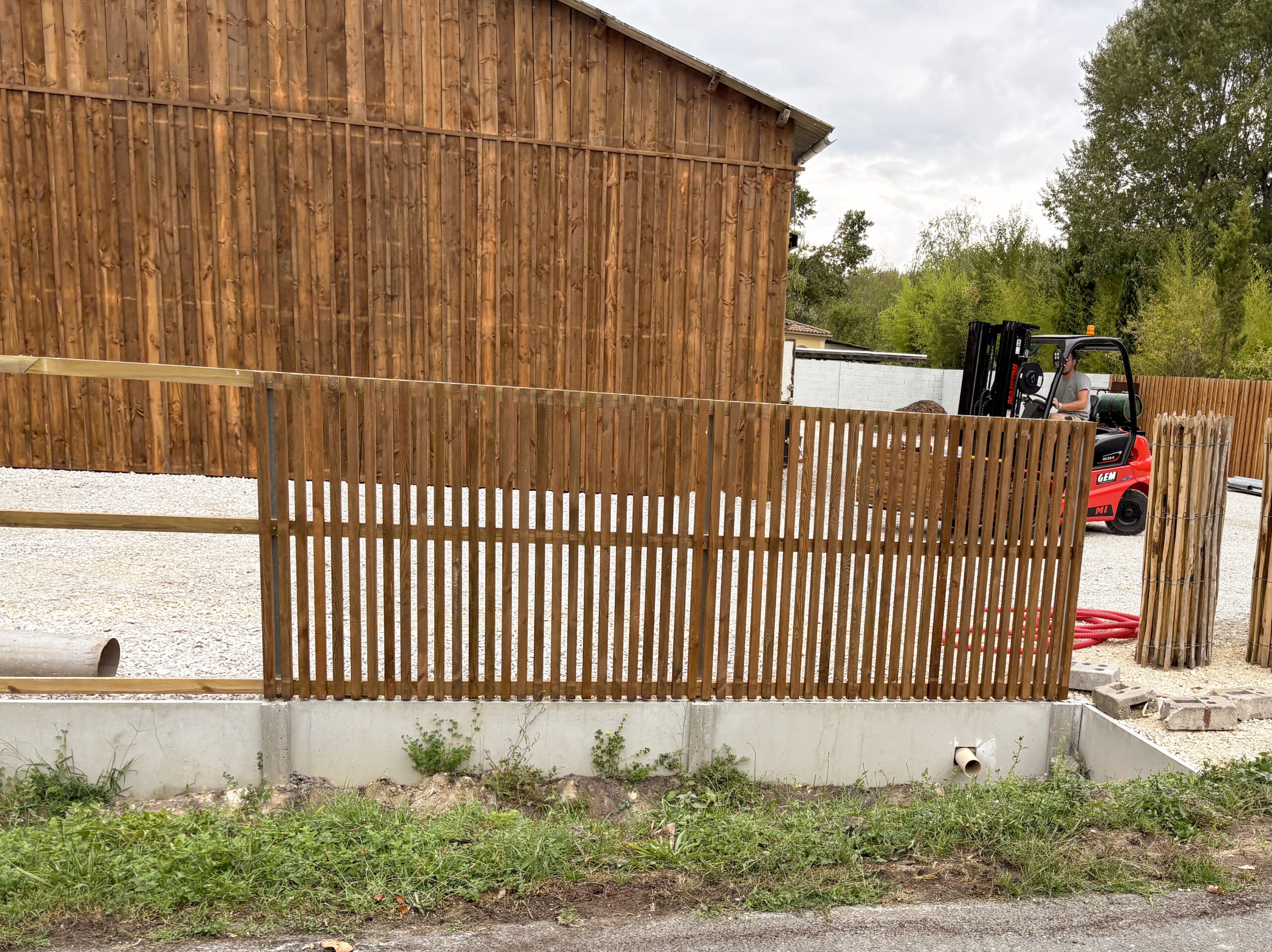 Clôture claire-voie en bois traité sur soubassement béton en cours de pose, réalisée par TO l'Atelier des Jardins, paysagiste à Bordeaux – création jardin sur-mesure