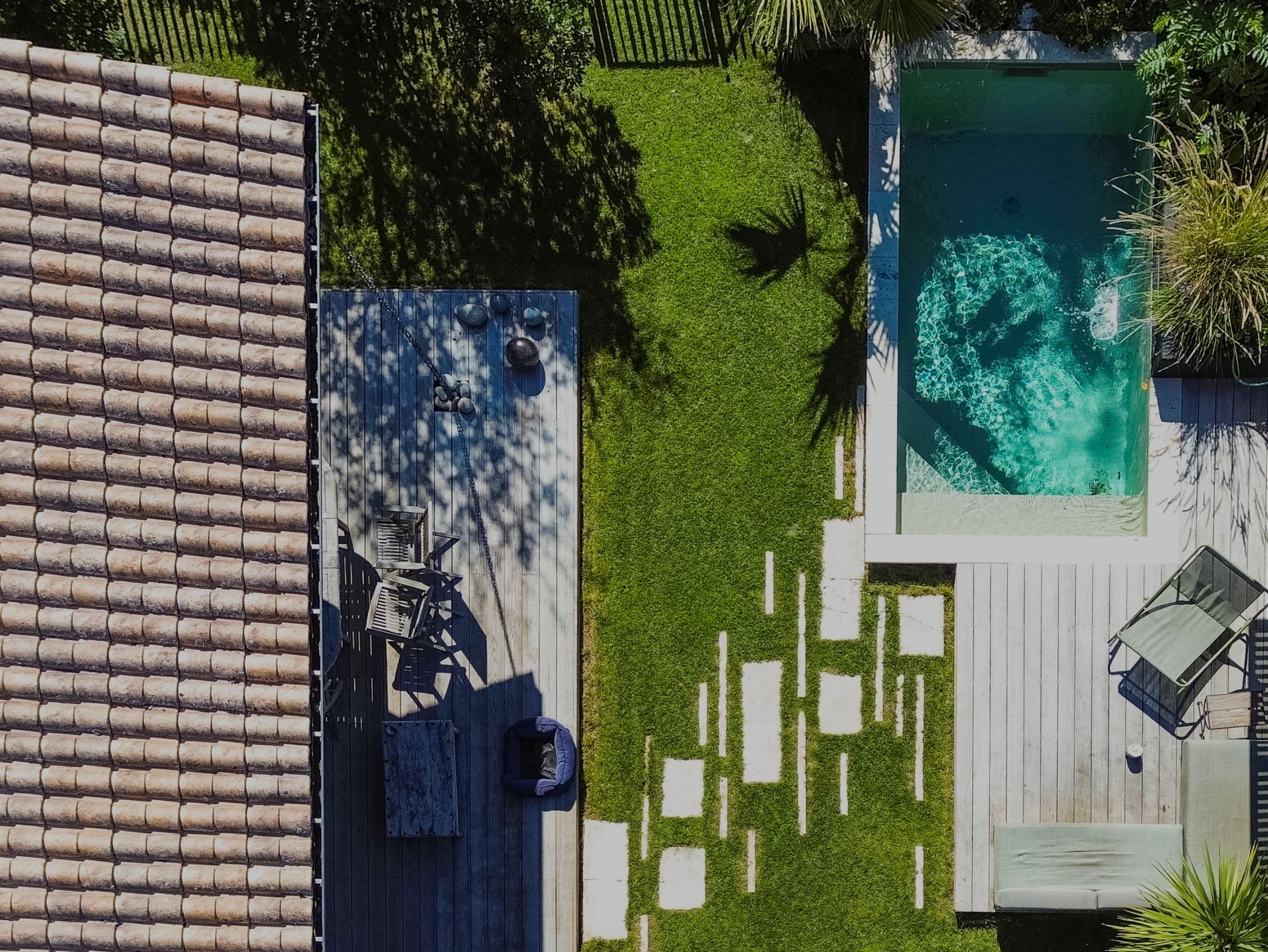 Vue aérienne par drone d'un aménagement de jardin avec piscine, terrasses en bois, pergola et pas japonais, réalisé par TO L'Atelier des Jardins, paysagiste à Bordeaux.